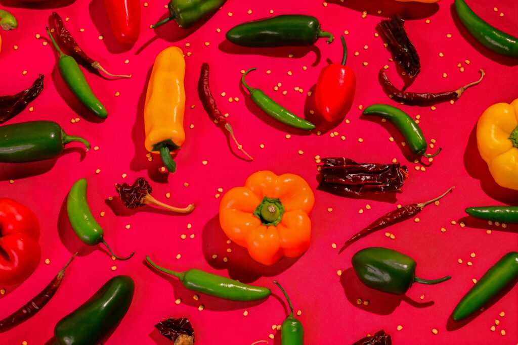 A vibrant collection of assorted chillies and bell peppers on a red background.