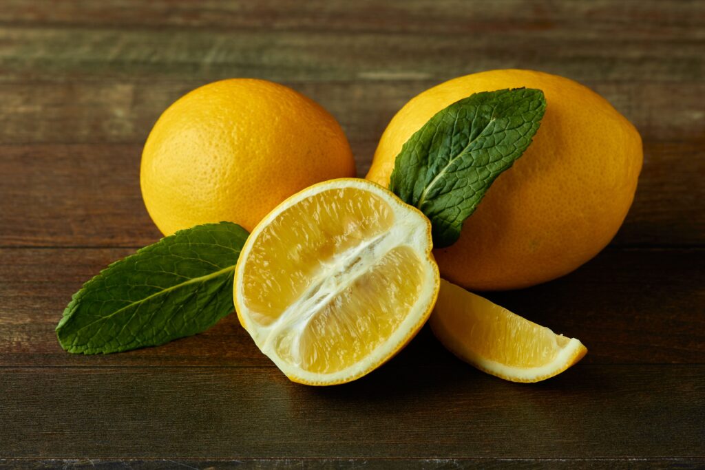 Close-up of sliced lemons and mint leaves on a rustic wooden background, highlighting freshness and organic appeal.